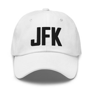Op de afbeelding: Witte baseballpet met zwarte geborduurde tekst "JFK".