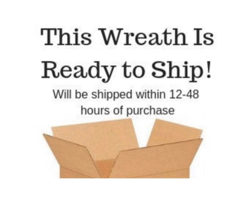 Op de afbeelding: Een bruine kartonnen doos met de bovenste kleppen open, waardoor een lege binnenkant zichtbaar is. De tekst "This Wreath Is Ready to Ship! Will be shipped within 12-48 hours of purchase" staat boven de doos gedrukt.