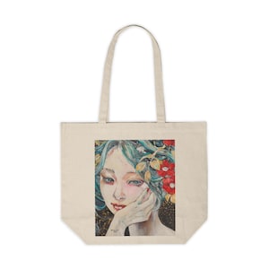 May include: A tote bag featuring a colourful illustration of a woman with blue hair and red flowers. The woman is looking to the side and has her hand on her chin.