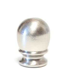 Könnte beinhalten: Ein metallischer silberner Endknopf mit einer glatten, abgerundeten Kuppeloberseite und einer ausgestellten, kreisförmigen Basis. Das Objekt weist eine polierte, reflektierende Oberfläche mit einem einheitlichen Finish auf.