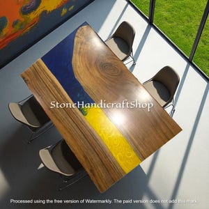 May include: A rectangular wooden table with a blue and yellow resin inlay. The table is surrounded by four chairs with gray seats and black metal legs. The table's dimensions are not visible in the image.