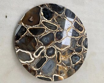 May include: Round agate coaster with a brown, black, and white pattern. The coaster is made of natural agate and has a polished finish.
