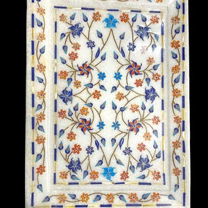 May include: A white marble serving tray with a floral design inlaid with blue, orange, and gold stones. The tray has a square shape with rounded corners.