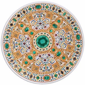 May include: A circular marble table top with an elaborate inlaid pattern. The design incorporates green, gold, and red elements, with oval and square forms. The centrepiece is a large green stone, and the outer edge is white.