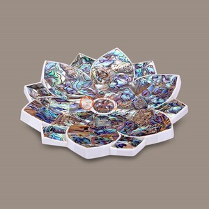 May include: A decorative lotus-shaped tray with a white border and a mosaic design. The mosaic is made of iridescent abalone shell pieces in shades of blue, green, and gold. The tray is a unique home decor item.