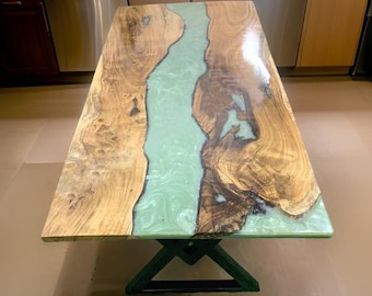 Puede incluir: Una mesa de madera con un río de epoxi verde que recorre el centro. La mesa tiene una base de metal negro.