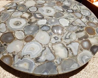 May include: A round table top made of agate, featuring a variety of gray and brown agate slices with a polished finish.