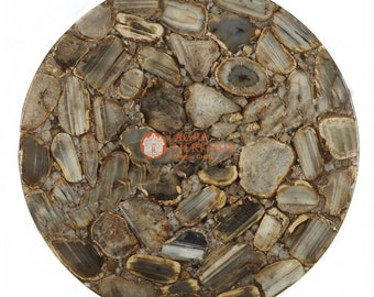 May include: A round table top made of natural stone, featuring a mosaic of irregularly shaped pieces in shades of gray, brown, and cream. The stone pieces are arranged to create a unique pattern. The table top is a decorative element for home decor.