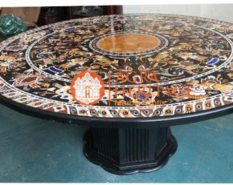 May include: Round black marble table with intricate inlaid designs in various colors. The table features a central circular design and a black pedestal base. The table's surface is highly polished, reflecting light.