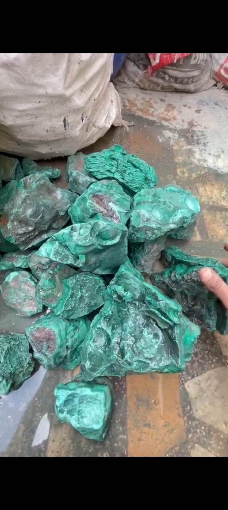 May include: A pile of rough, green malachite stones. The stones are various sizes and shapes, with some showing a darker green color.