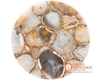May include: A round tabletop made of agate stone. The surface is a mosaic of beige, white, and brown agate slices, creating a natural, patterned design. The agate pieces are arranged to form a circular shape.