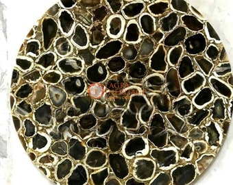 May include: A round decorative tabletop with a mosaic design. The tabletop features a pattern of dark brown and black agate stones set in a white matrix. The stones are irregularly shaped and create a unique, natural look. The logo "AGRA HERITAGE Marble Craft" is visible.