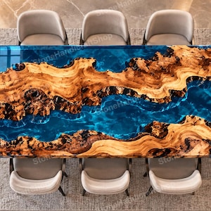 May include: A rectangular dining table featuring a live edge wood slab with a prominent natural grain pattern, bisected by a translucent, deep blue epoxy resin river design. The table is surrounded by six light gray upholstered dining chairs.