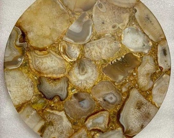 May include: Round agate coaster with a natural, organic pattern of brown and white agate slices. The coaster has a glossy finish and is perfect for protecting surfaces from heat and scratches.