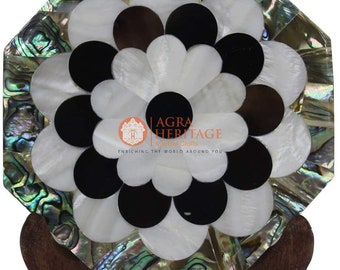 May include: An octagonal decorative coaster with a floral design. The coaster features a mosaic of white, black, and brown circular pieces, surrounded by iridescent abalone shell. It rests on a wooden stand. The logo "Agra Heritage" is visible.