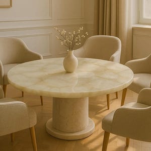 May include: A circular dining table with a light-coloured, patterned top and a cylindrical base. Six beige upholstered chairs surround the table. A vase with decorative branches sits on the table. The room has a neutral colour palette.