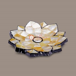 Puede incluir: Un cuenco decorativo con forma de loto y diseño de mosaico. El cuenco presenta un patrón de piezas de concha blancas y amarillas, delineadas con bordes negros. Una pieza única de decoración del hogar.