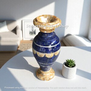 May include: A decorative vase with a blue and beige mosaic design. The vase has a wide, flared top and a rounded body. The base and top are beige, while the body is a deep blue with white and beige accents. A small succulent in a white pot sits nearby.