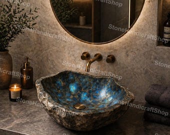 May include: A unique, natural stone sink with a rough, textured exterior and a vibrant blue and green interior. The sink is set on a dark countertop with a gold faucet and a round mirror in the background. The sink is a beautiful addition to any bathroom.