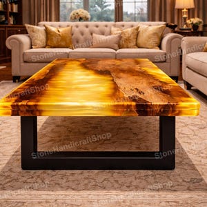 May include: A rectangular coffee table with a glowing amber-colored top and a black metal base. The table's surface has a natural, textured appearance, and it is set in a living room with neutral-toned furniture.