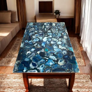 May include: A coffee table with a blue agate stone top. The table has a dark wood base and is sitting on a rug.