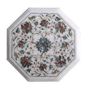 Puede incluir: Tapa de mesa octogonal de mármol blanco con un intrincado diseño floral incrustado con nácar y piedras de colores.