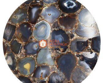 May include: Round agate stone table top with a mosaic pattern of gray, blue, and brown tones. The surface features a polished finish with a gold-colored resin filling the gaps between the stones. The logo "Agra Heritage Marble Crafts" is visible.