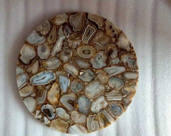 May include: A round agate coaster with a brown and white pattern. The coaster is made of natural agate and has a unique, organic look.