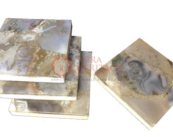 Puede incluir: Un juego de posavasos cuadrados con apariencia de piedra natural. Los posavasos presentan una mezcla de tonos beige, gris y blanco con patrones únicos. Los bordes son de un color más claro, y el juego incluye cuatro posavasos.