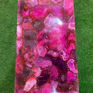 May include: Pink and purple agate slab with a polished surface. The slab has a natural, organic pattern with swirls and veins of color.