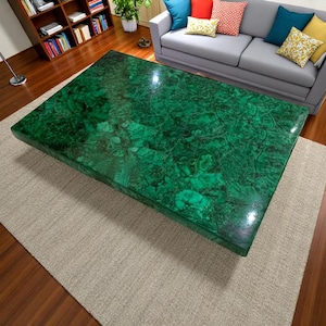 May include: A large, rectangular coffee table with a green malachite top. The table has a polished, glossy finish and intricate patterns throughout the surface.