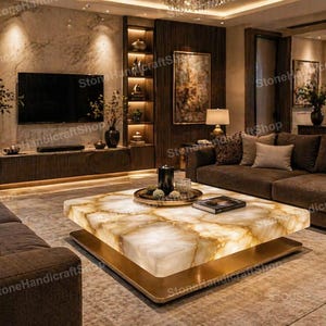 May include: A luxurious living room featuring a large, illuminated onyx coffee table with a gold base. The room includes a dark brown sofa, a large flat-screen TV, and built-in shelving with decorative items. The overall aesthetic is modern and elegant.