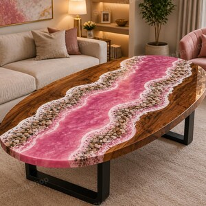 Puede incluir: Una mesa de centro ovalada con una losa de madera natural y un diseño de río central hecho de resina rosa y piedras incrustadas. La mesa se apoya sobre dos patas de metal negro en forma de U, con un acabado pulido y un borde orgánico.