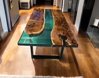 Puede incluir: Una mesa de madera grande con un río de epoxi verde que atraviesa el centro. La mesa tiene una base de metal negro.
