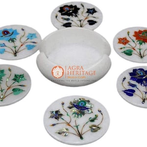 Könnte beinhalten: Set aus sechs weißen Marmoruntersetzern mit floralen Intarsien in verschiedenen Farben, darunter Blau, Grün, Orange und Schwarz. Die Untersetzer sind rund und werden mit einem passenden Halter geliefert.