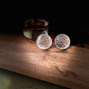 Op de afbeelding: Twee heldere glazen golfballen op een houten oppervlak.