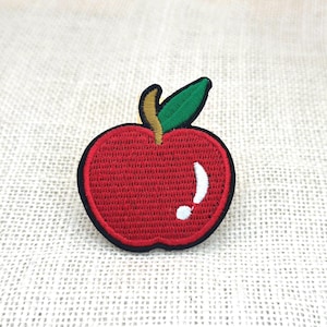 以下が含まれることがあります： 黒い縁取りの赤いリンゴの刺繍パッチ。リンゴには緑の葉、黄色の茎、白いハイライトがあります。このパッチは、衣類、バッグ、その他の布地アイテムに適しています。