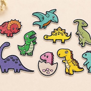 May include: A collection of nine embroidered dinosaur patches in various colours including red, teal, green, yellow, purple, and pink. Each patch features a distinct cartoon-style dinosaur design with a white border, suitable for fabric application.