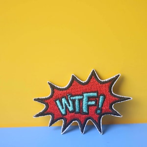 May include: A red and black embroidered patch with a white exclamation point and the text "WTF!" in blue.