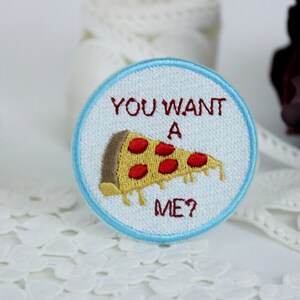 May include: A white embroidered patch with blue stitching. The patch features a slice of pizza with red pepperoni and the text "You want a me?"
