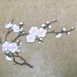 Op de afbeelding: Geborduurde bloemenpatch met een tak met witte en roze bloesems. De patch heeft een bruine stengel en is geplaatst tegen een neutrale achtergrond. Ideaal voor het toevoegen van een decoratief tintje aan kleding of accessoires.