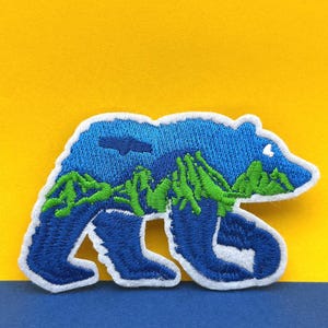 Broderad lapp med Blue Bear Mountain-motiv: Applikation för vildmarksvandring