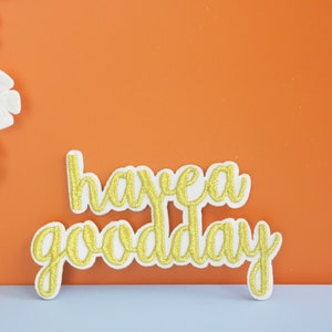 May include: White background with a white crocheted doily on the left side of the image. The words "have a good day" are written in gold glitter letters on a white background.