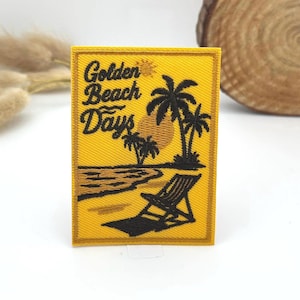 May include: A yellow rectangular patch with the words "Golden Beach Days" in black script. The patch depicts a beach scene with palm trees, a sun, and a beach chair. It is likely an iron-on or sew-on patch.
