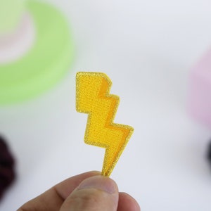May include: A yellow lightning bolt shaped patch with a glittery finish.
