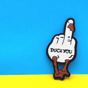 May include: White embroidered patch of a goose giving the middle finger with the text "Duck You" on a blue and yellow background.