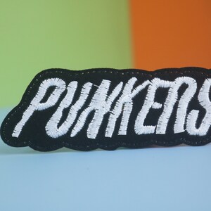 Może przedstawiać: Czarna naszywka haftowana z białymi ściegami, na której widnieje napis "PUNKERS".