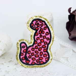 Può includere: Toppa ricamata a ferro da stiro di leopardo rosa e nero con bordatura dorata glitterata.