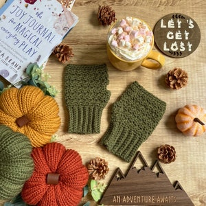 May include: A pair of green fingerless crochet mittens, a mug of hot chocolate with marshmallows, a wooden sign that says "Let's Get Lost", and a wooden sign that says "An Adventure Awaits".