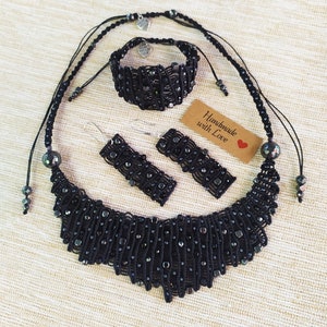 May include: Black necklace, bracelet, and earrings set with black beads and silver accents. The set is handmade and comes with a tag that says "Handmade with Love".